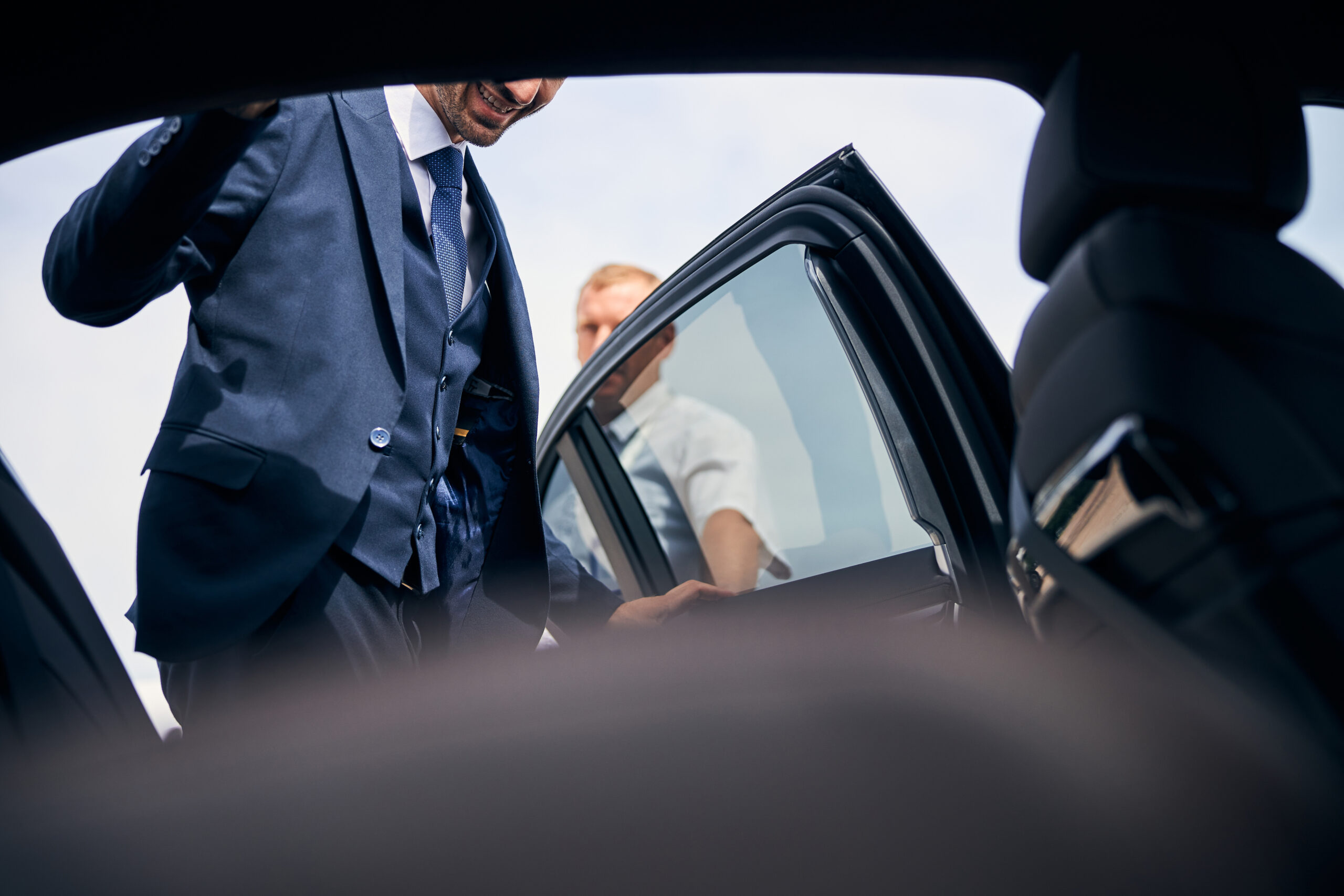 Cheerful businessman getting into a backseat of a car